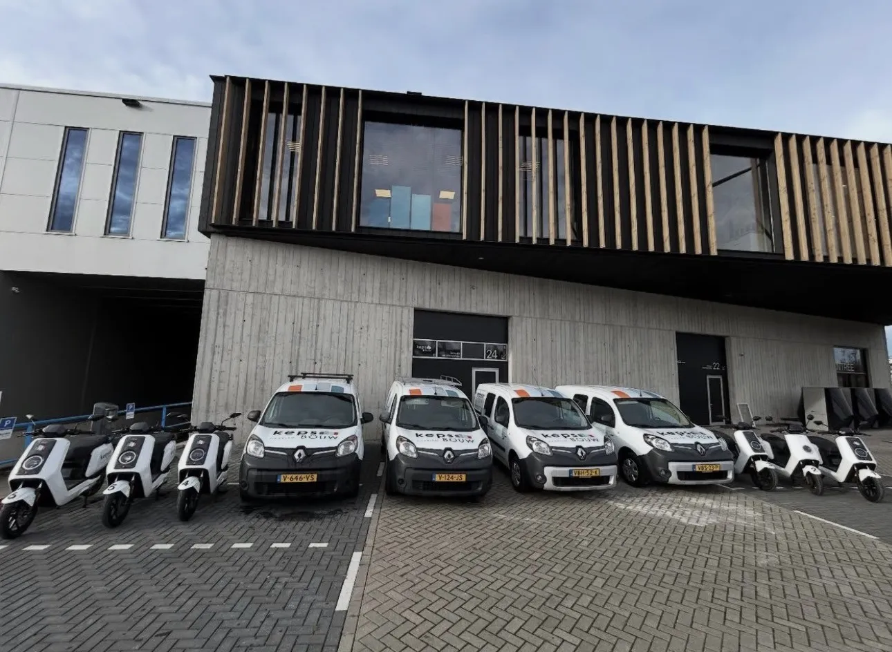 Elektrische bedrijfsbussen en scooters van Keps Bouw bij het pand in Haarlem